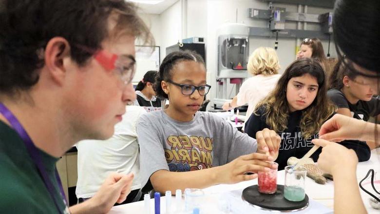 Several youth work with colored fluids in a lab at Penn State Behrend